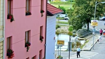 A pink building with multiple windows, a sign indicating a hotel, and a car parked on the street.