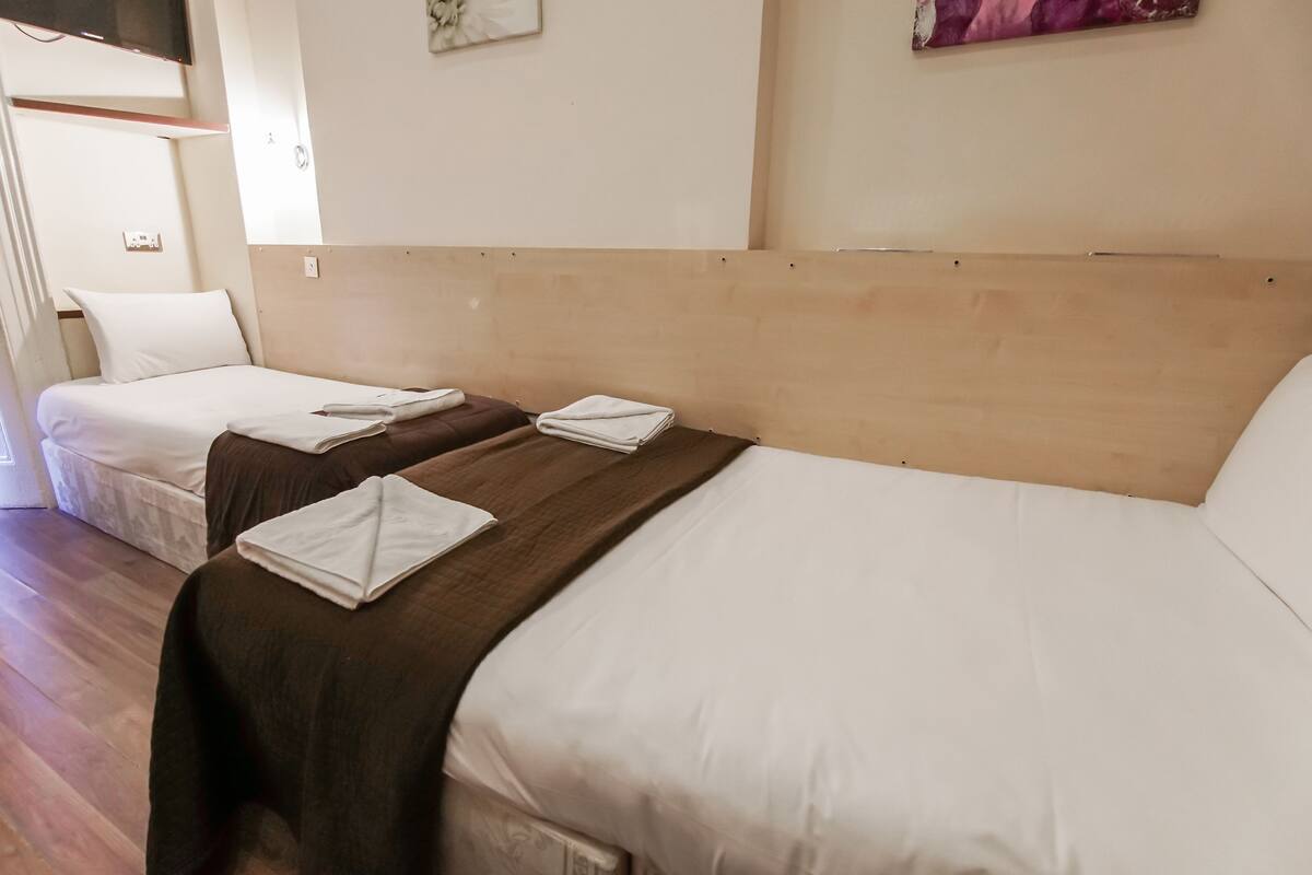 A hotel room with two beds, each with white linens and brown headboards.