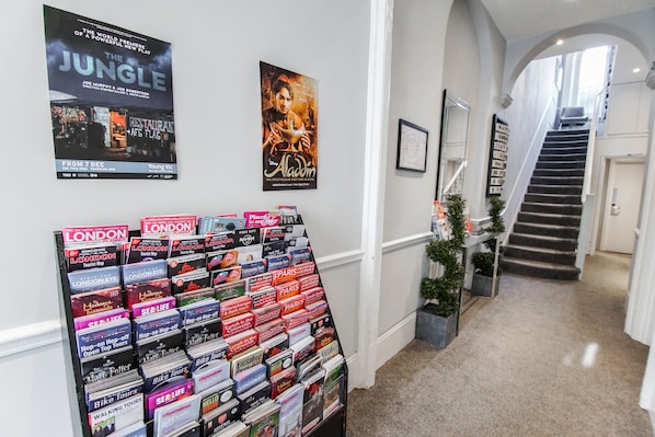 Un pasillo con una escalera, carteles en las paredes y una exhibición de folletos de viaje.