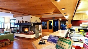 A cozy living room with a fireplace, green sofas, and a wooden ceiling. - Hotel Santa Caterina (Valfurva)