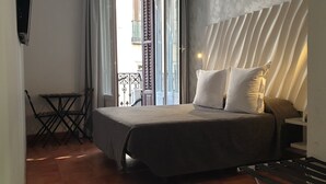 Un dormitorio con una cama, una mesita y vistas al exterior.