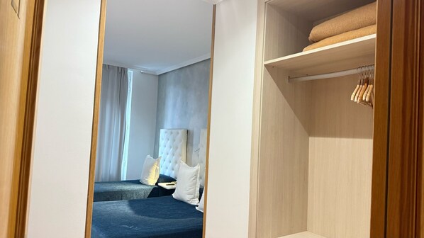 Una habitación de hotel con una cama, un armario y un espejo.