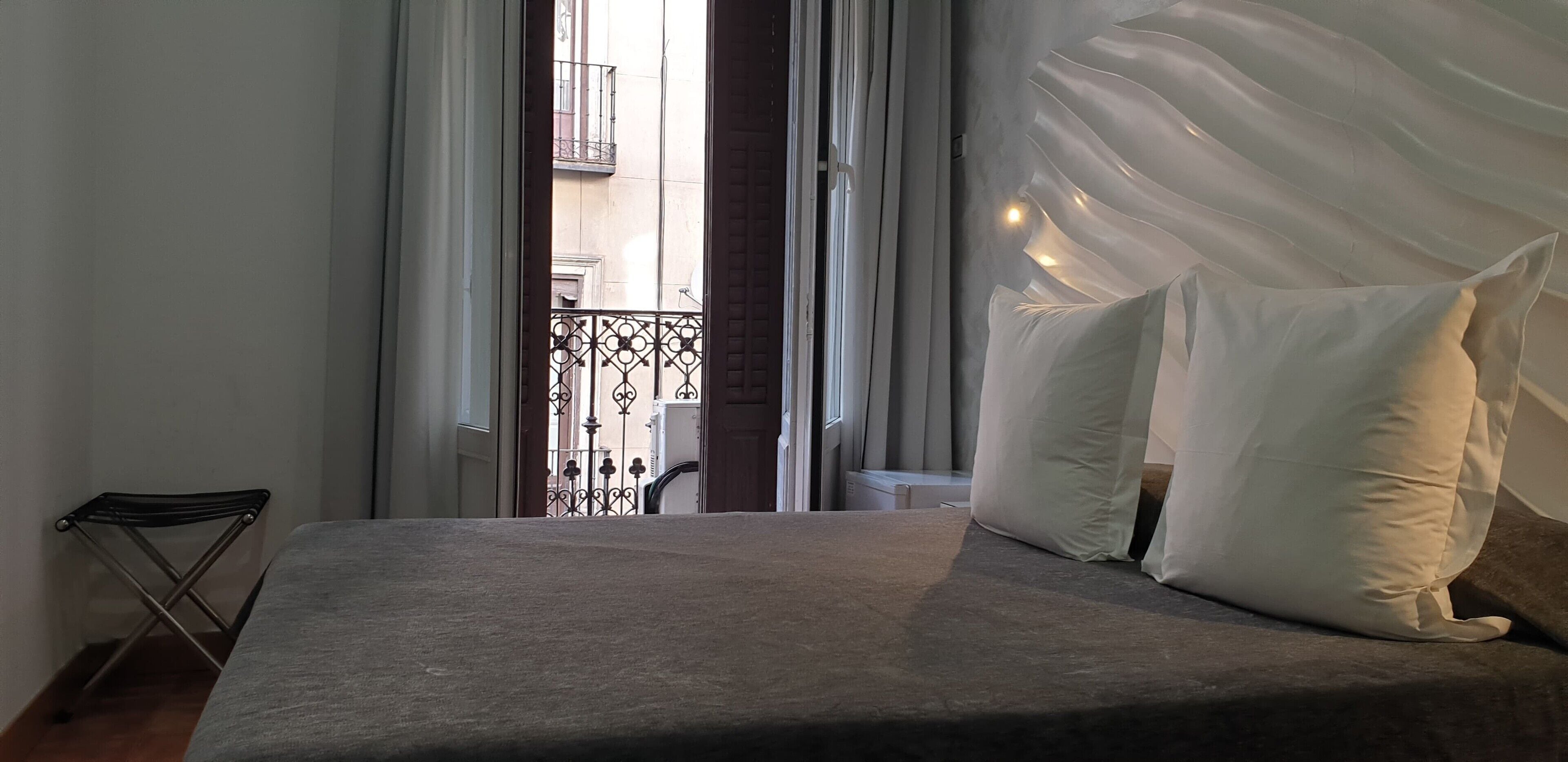Ein Schlafzimmer mit einem Bett, weißen Kissen und transparenten Vorhängen.