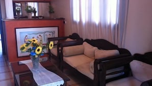 A living room with a sofa, a coffee table with a vase of sunflowers, and a framed picture on the wall. - Hotel Lignos (Santorini)