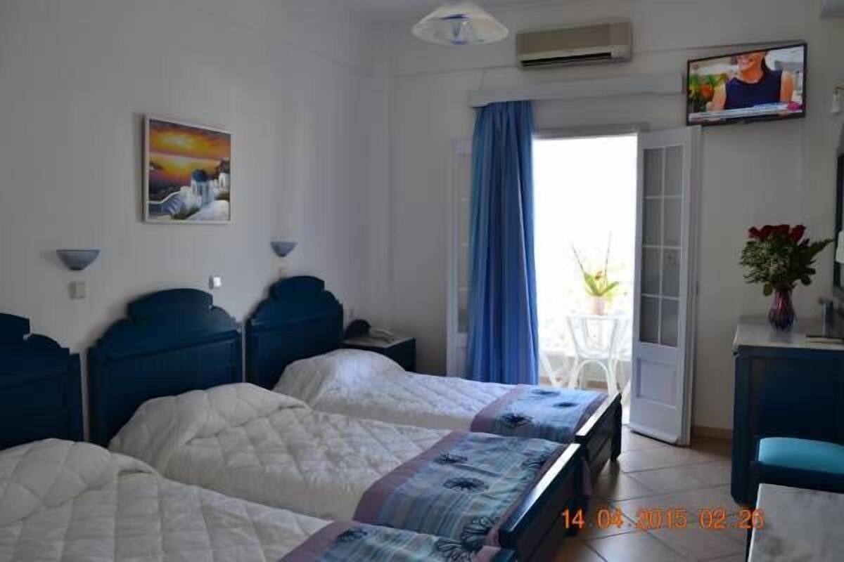 A hotel room with two beds, a TV, a painting, and a view of the outside.