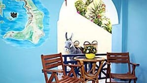 A room with a round table, four wooden chairs, a small potted plant, and a wall map. - Hotel Lignos (Santorini)