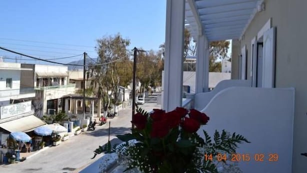 A street view with a white building, a covered walkway, and a row of shops. - Hotel Lignos (Santorini)