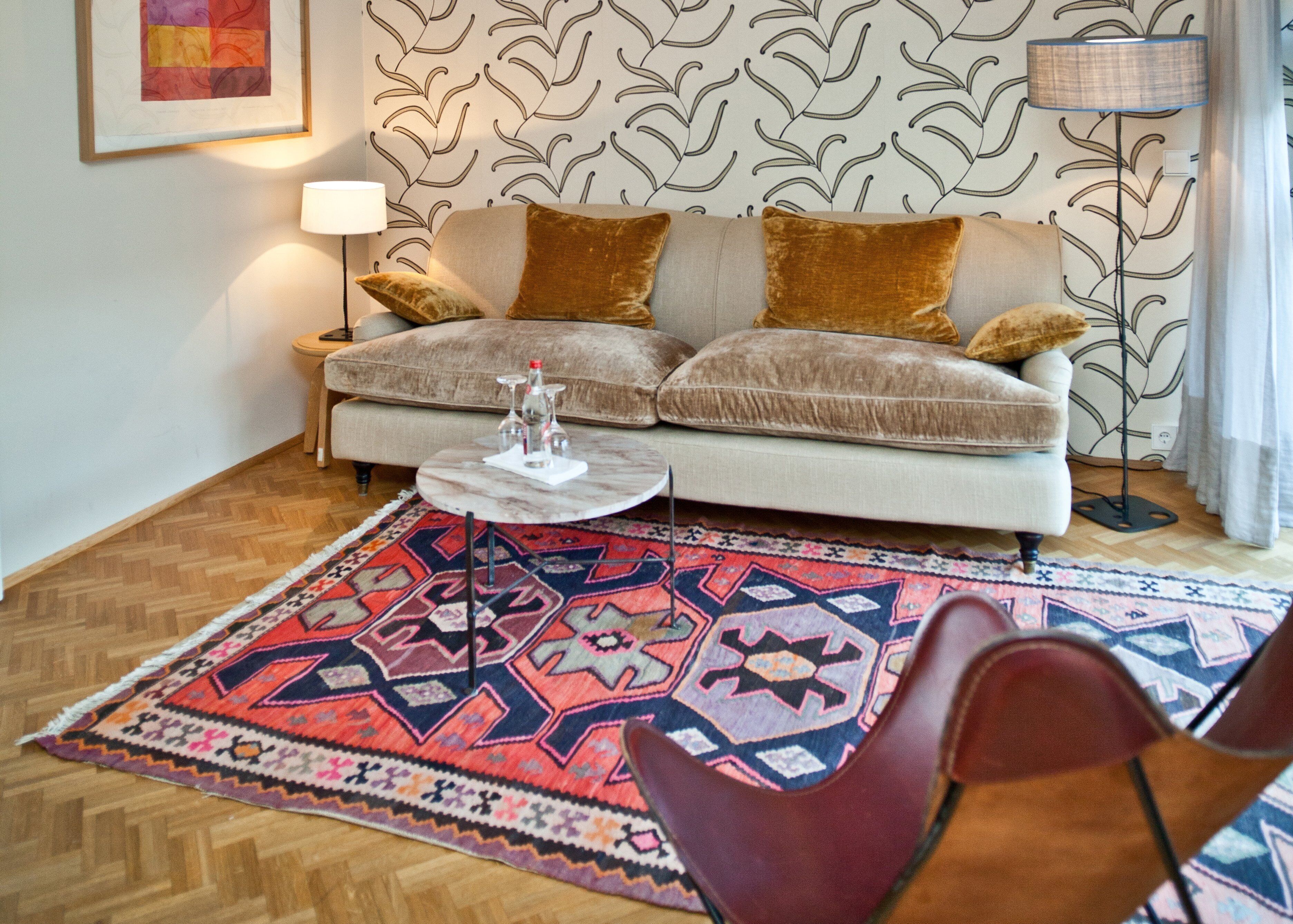Una sala de estar con un sofá, una mesa de centro, un tapete estampado y una silla.