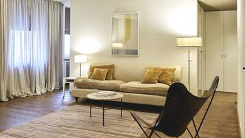 A modern living room with a sofa, a coffee table, a chair, a lamp, and a large mirror on the wall.