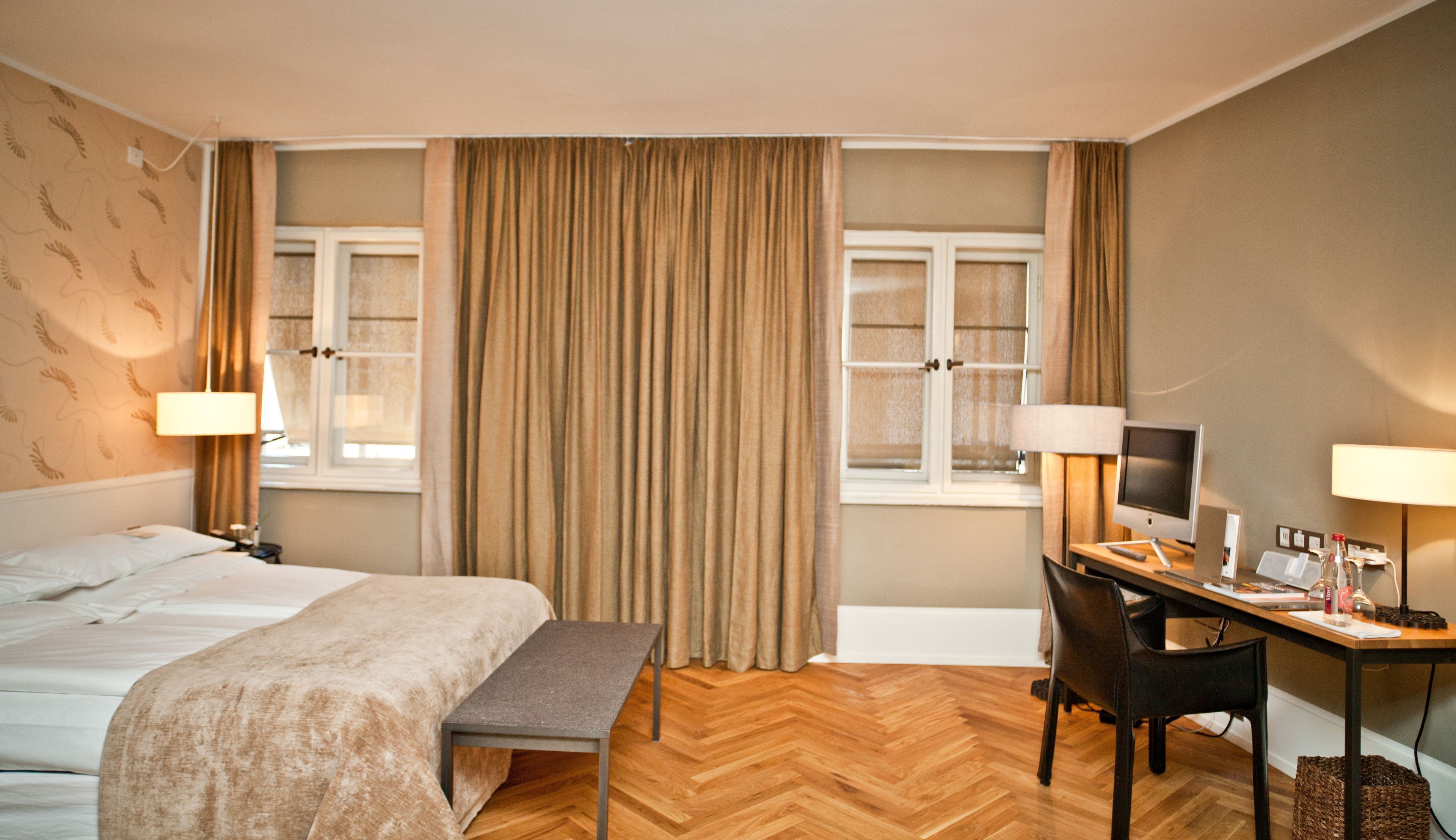 A hotel room with a bed, desk, chair, and a television.