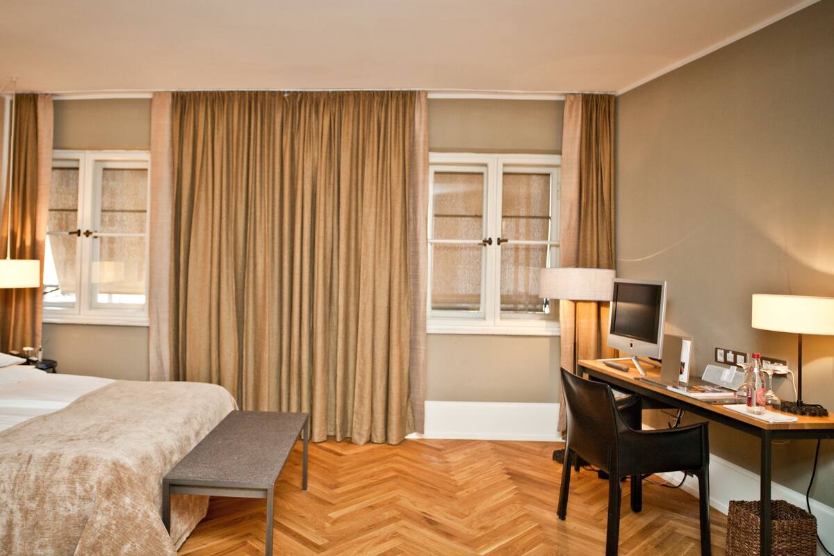 A hotel room with a bed, desk, chair, and a television.