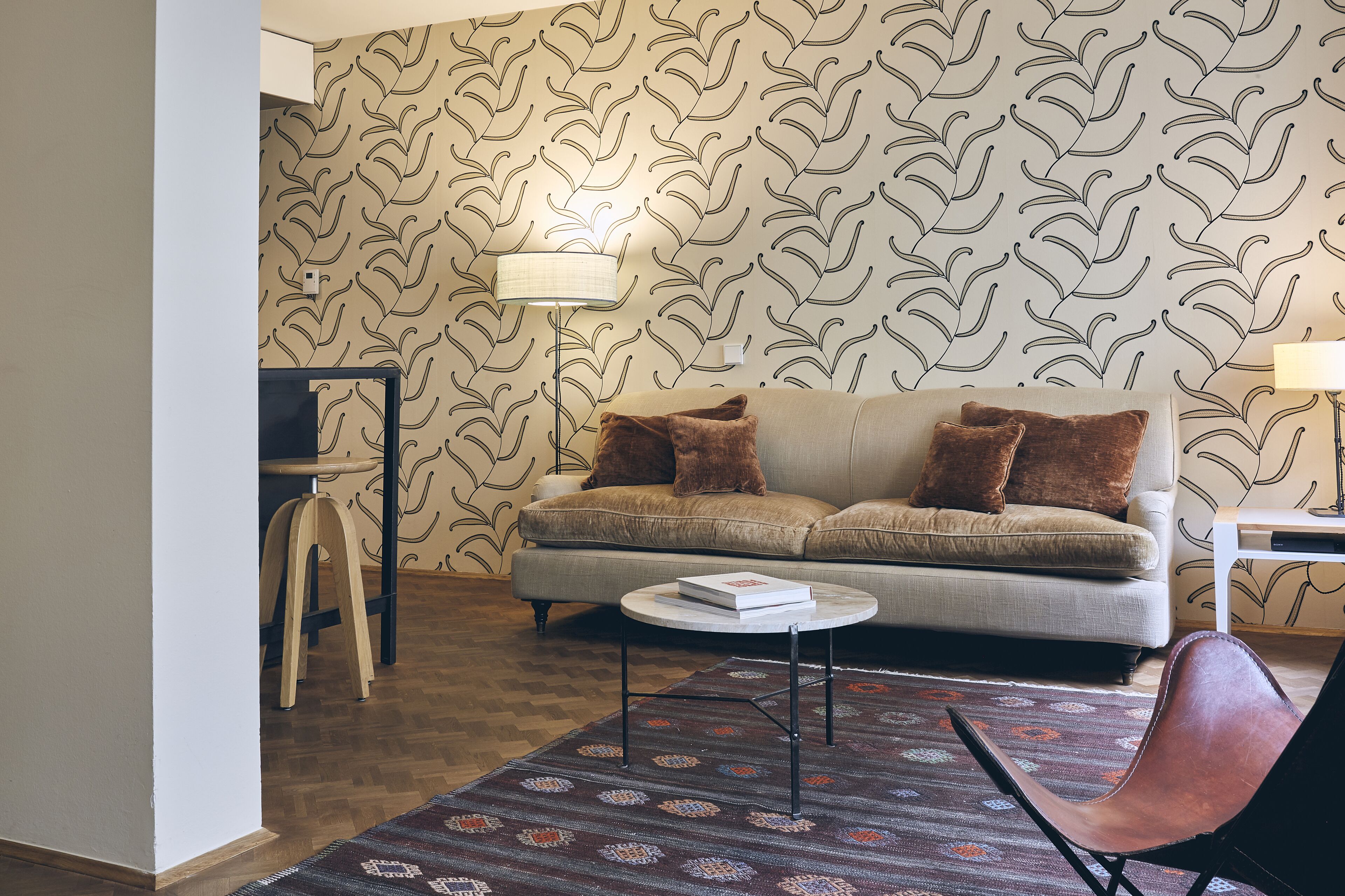 A living room with a sofa, a coffee table, a patterned rug, and a chair.