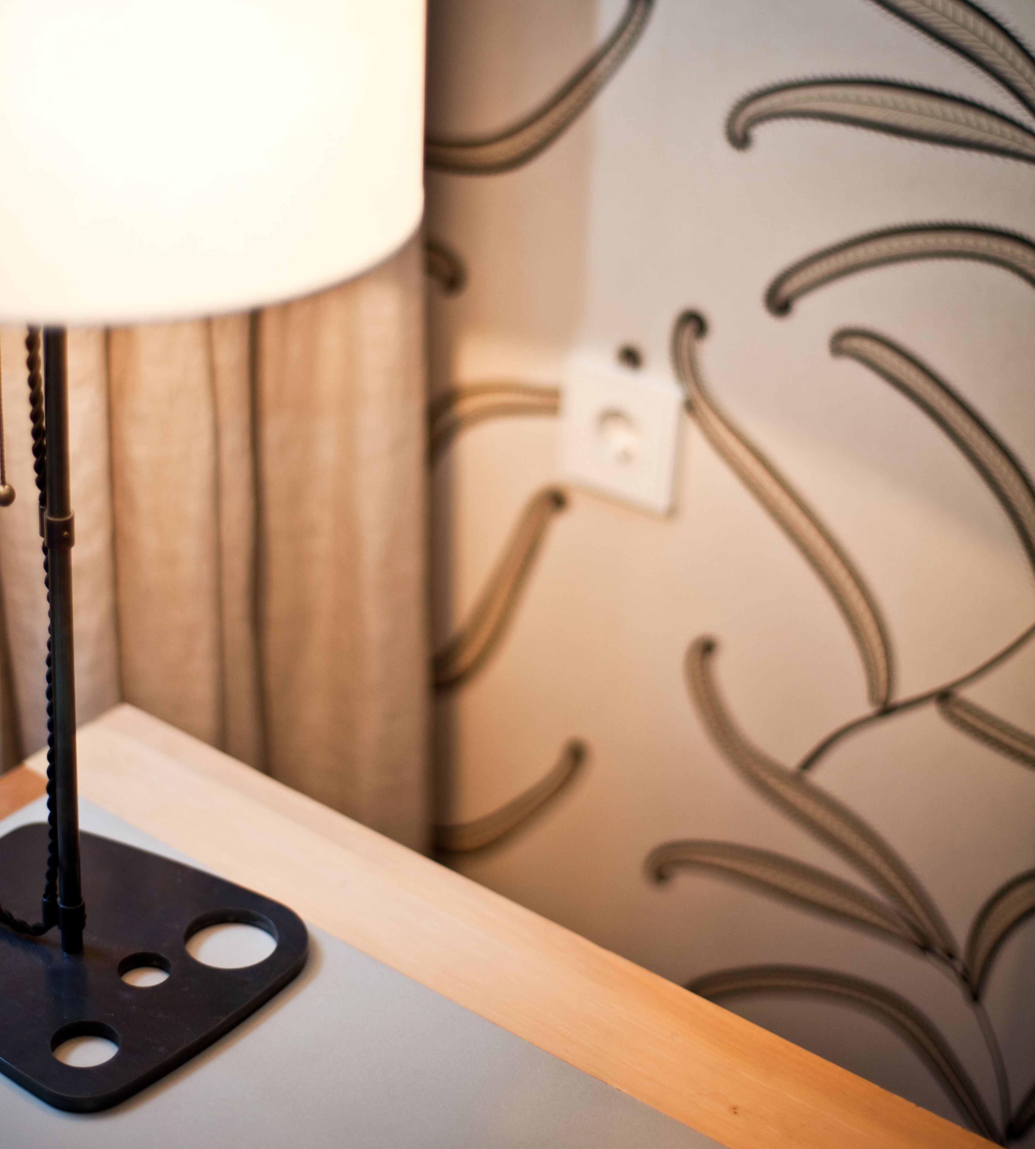 A lamp on a table with a patterned wallpaper in the background.