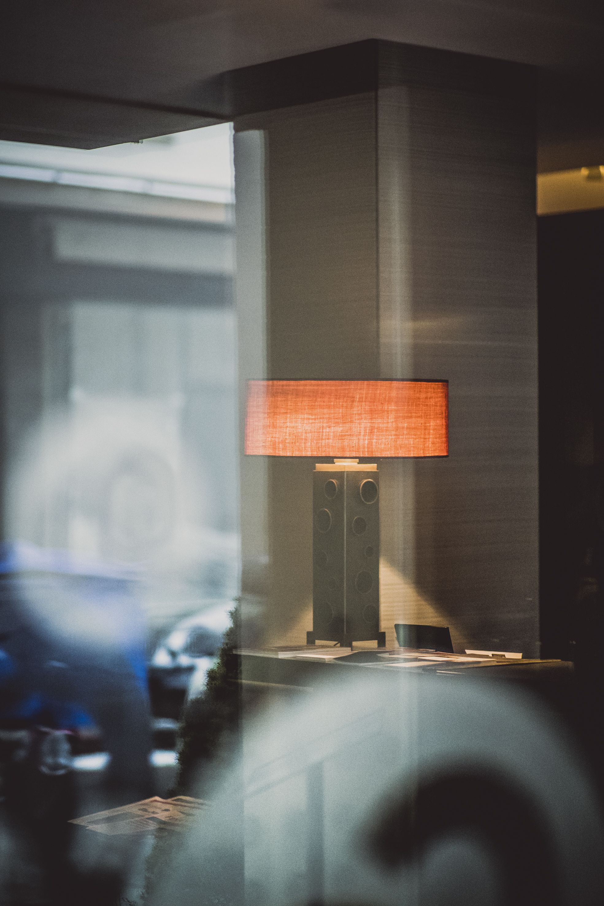 A modern lamp with a rectangular shade on a stand, positioned against a wall.