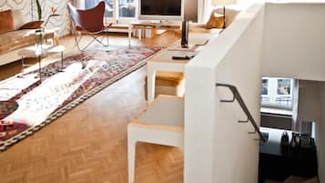 Ein modernes Wohnzimmer mit einer Couch, einem roten Sessel, einem Fernseher und einer Treppe.