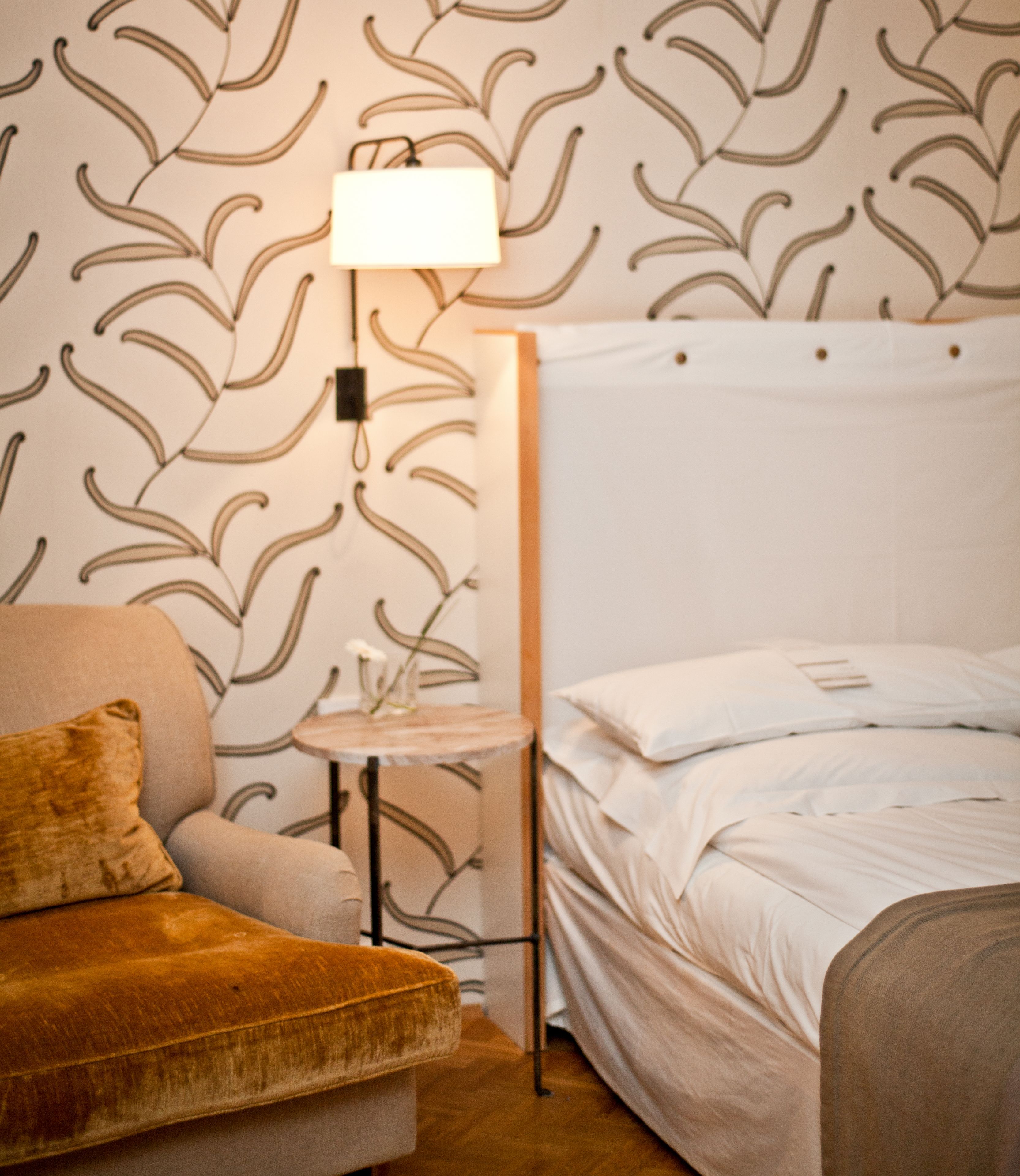Un dormitorio con una cama, una mesita de noche, una lámpara y un sofá.
