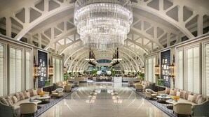 A spacious lobby with high ceilings, a large chandelier, and seating areas.