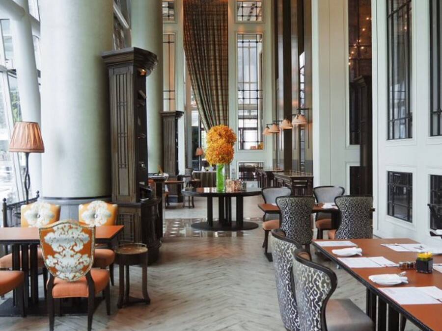 A spacious hotel lobby with high ceilings, large windows, and a herringbone floor pattern.