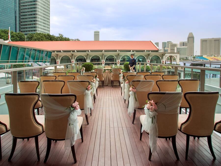 A deck with rows of chairs arranged for an event, overlooking a cityscape with modern buildings.