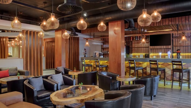 A modern lounge area with leather sofas, wooden tables, and hanging pendant lights.