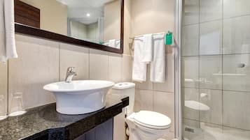 A bathroom with a sink, toilet, and glass shower enclosure.