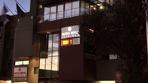 A modern hotel with a glass facade, a visible parking entrance, and a sign indicating it is a hotel.