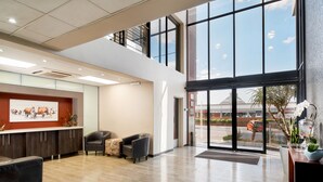 A spacious lobby with a reception desk, seating area, and large windows offering a view of the outside.