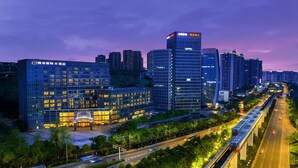 A modern cityscape with high-rise buildings, a prominent train station, and a well-lit urban environment.