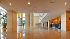 A spacious lobby with a polished floor, large windows, and a reception desk.