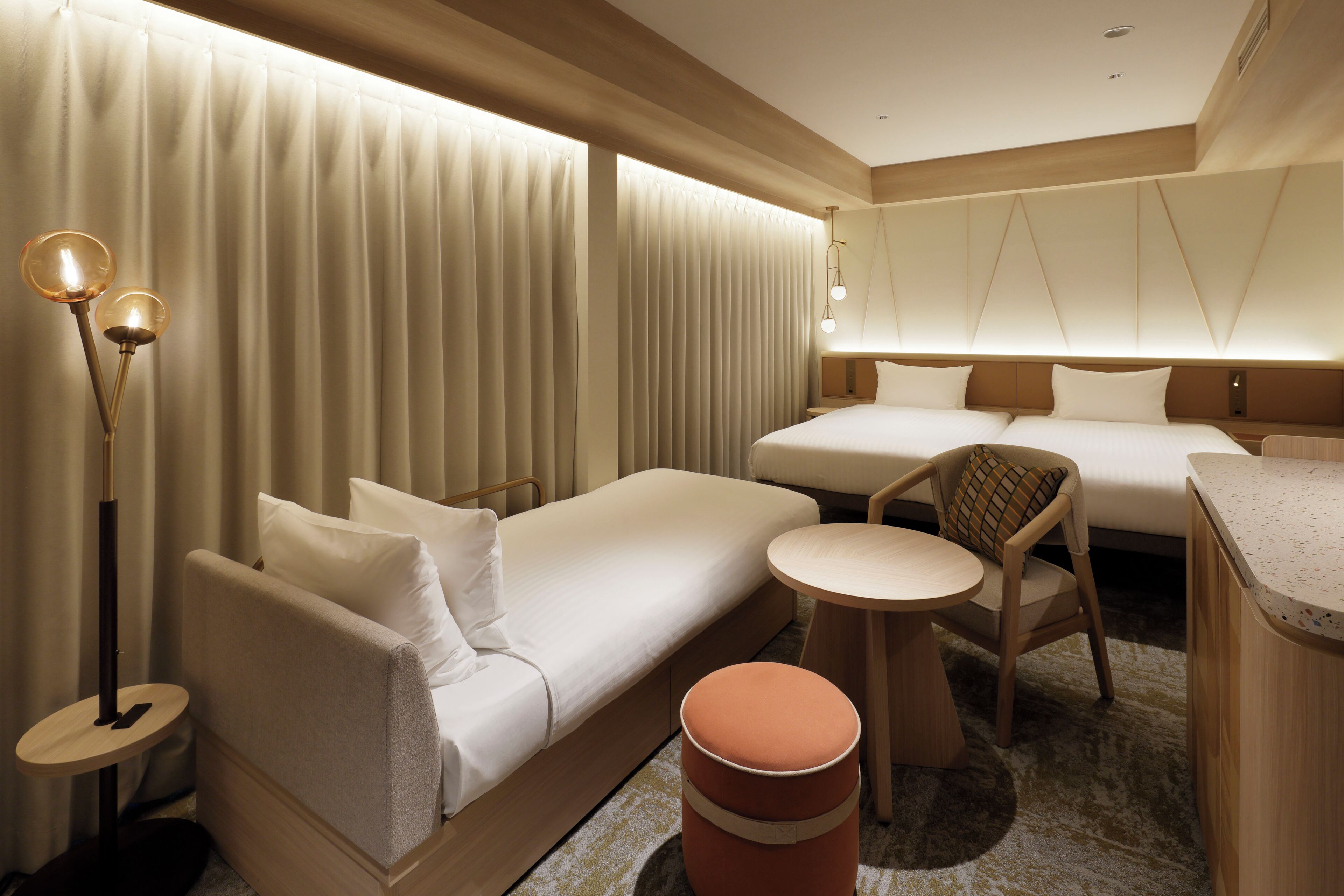 Habitación de hotel con sofá cama, una mesita redonda, una silla y una cama grande.