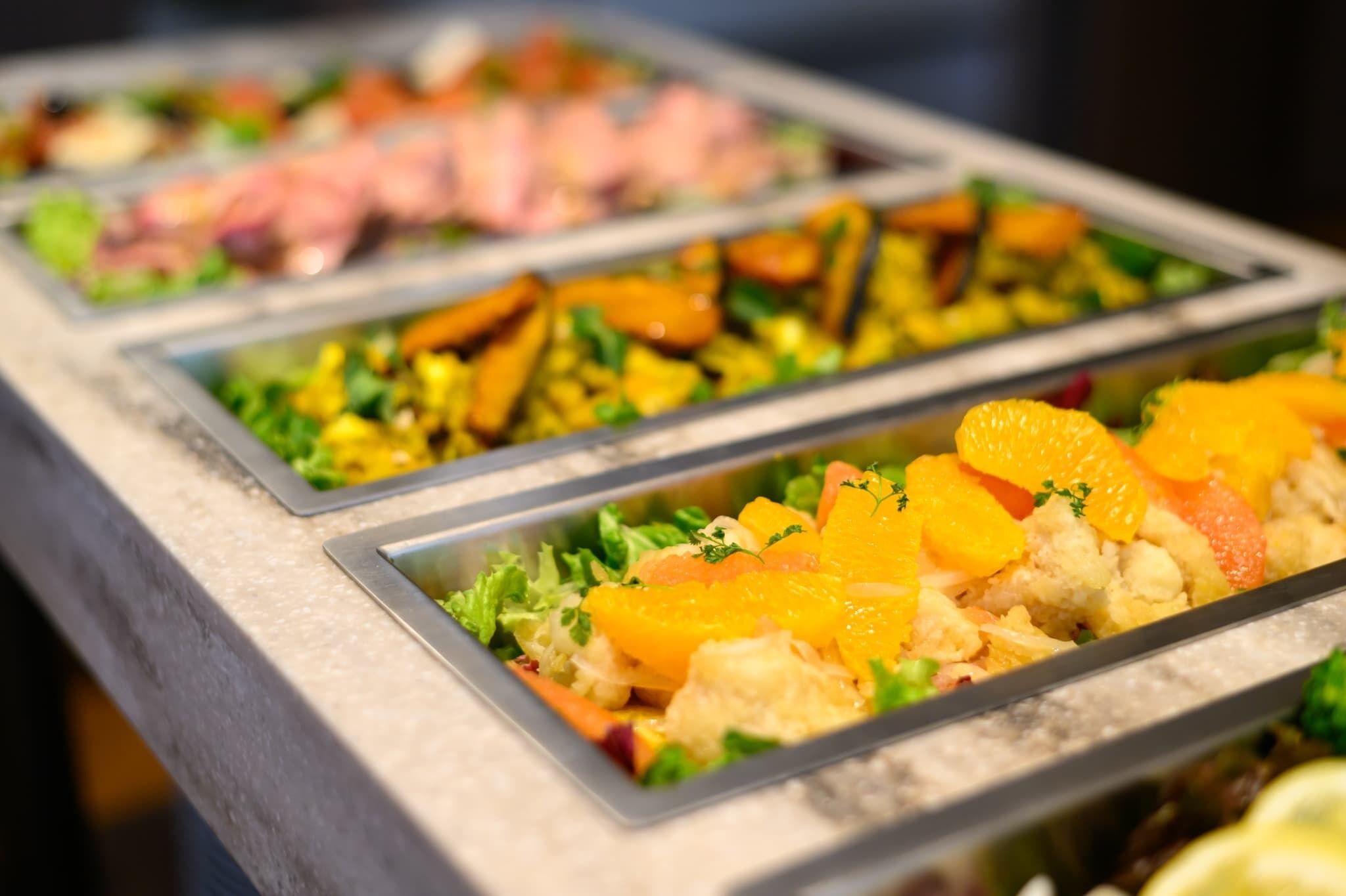 Un buffet proposant une variété de plats, notamment des fruits de mer, des légumes et des fruits.