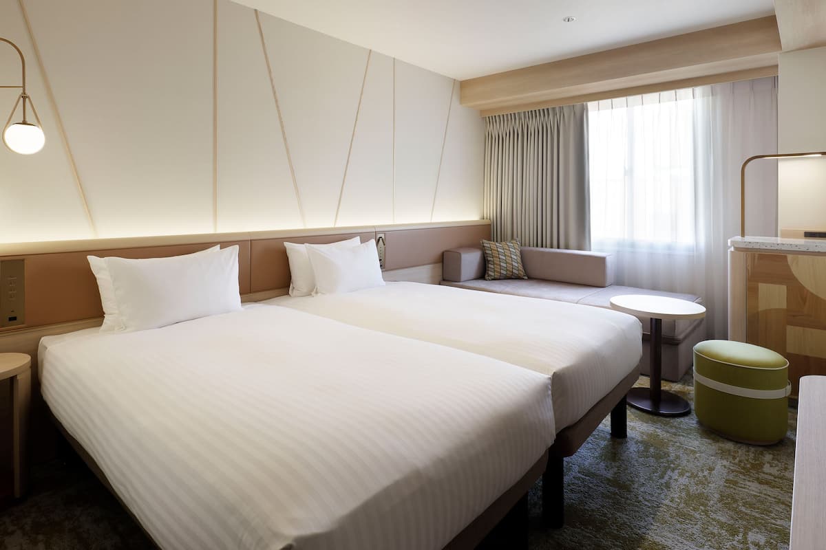 Quarto de hotel com uma cama grande, um sofá, uma mesa pequena e uma escrivaninha.