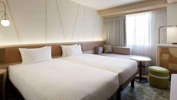 A hotel room with a large bed, a sofa, a small table, and a desk.