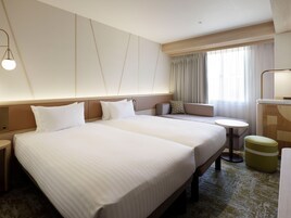 A hotel room with a large bed, a sofa, a small table, and a desk.