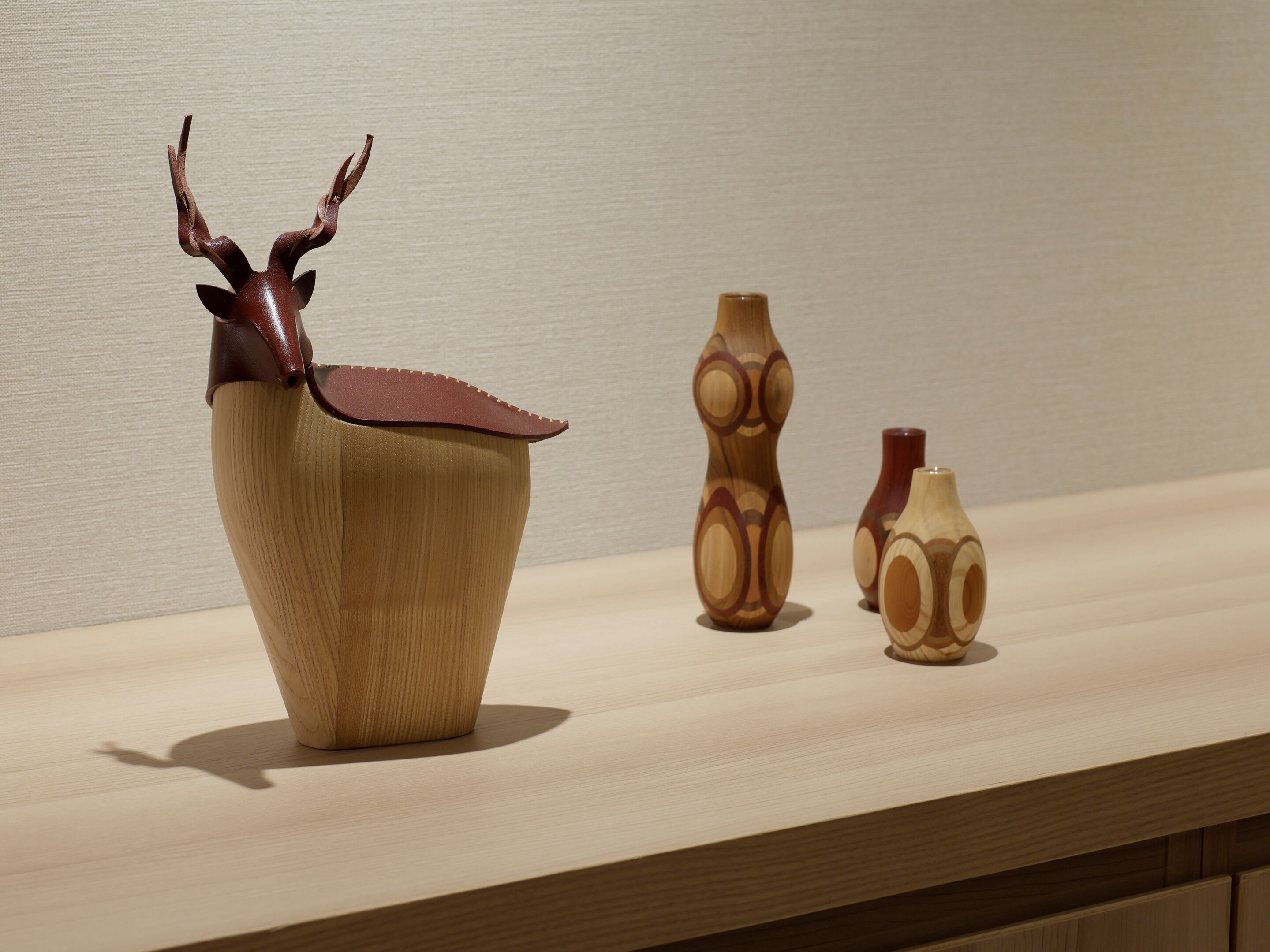 A wooden shelf with three vases of varying shapes and sizes.