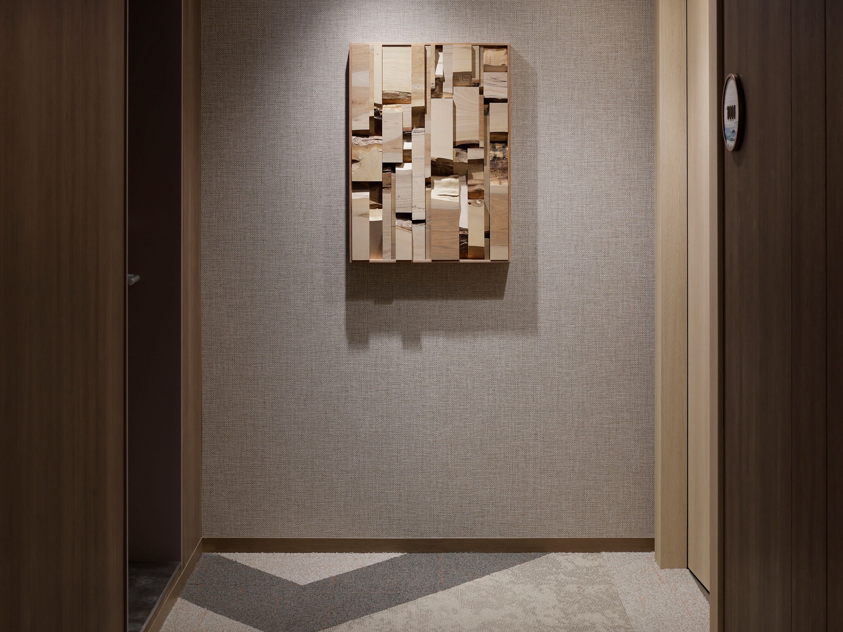 A hallway with a textured wall and a geometric wooden art piece.