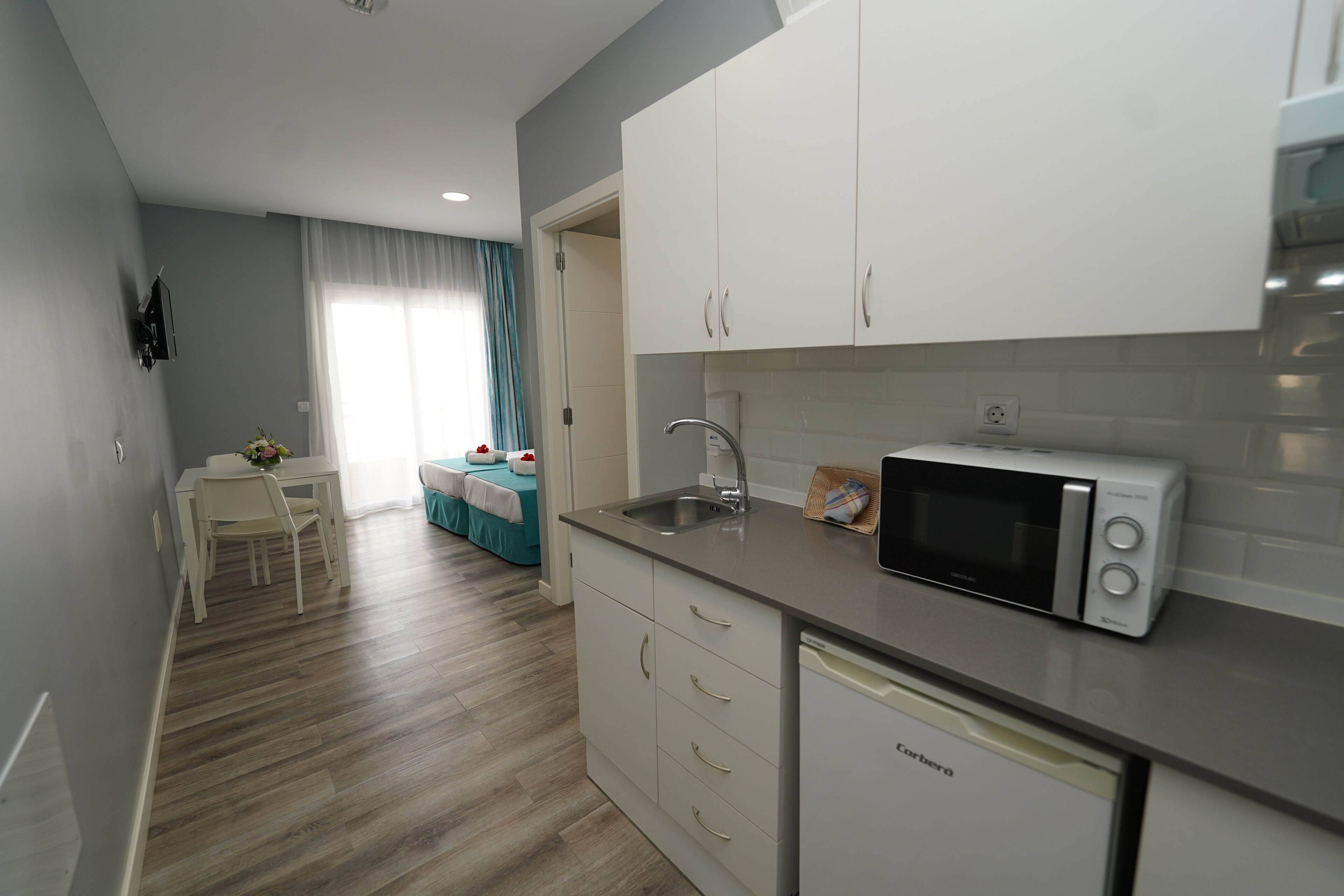 A modern kitchen with white cabinets, a dishwasher, and a microwave.