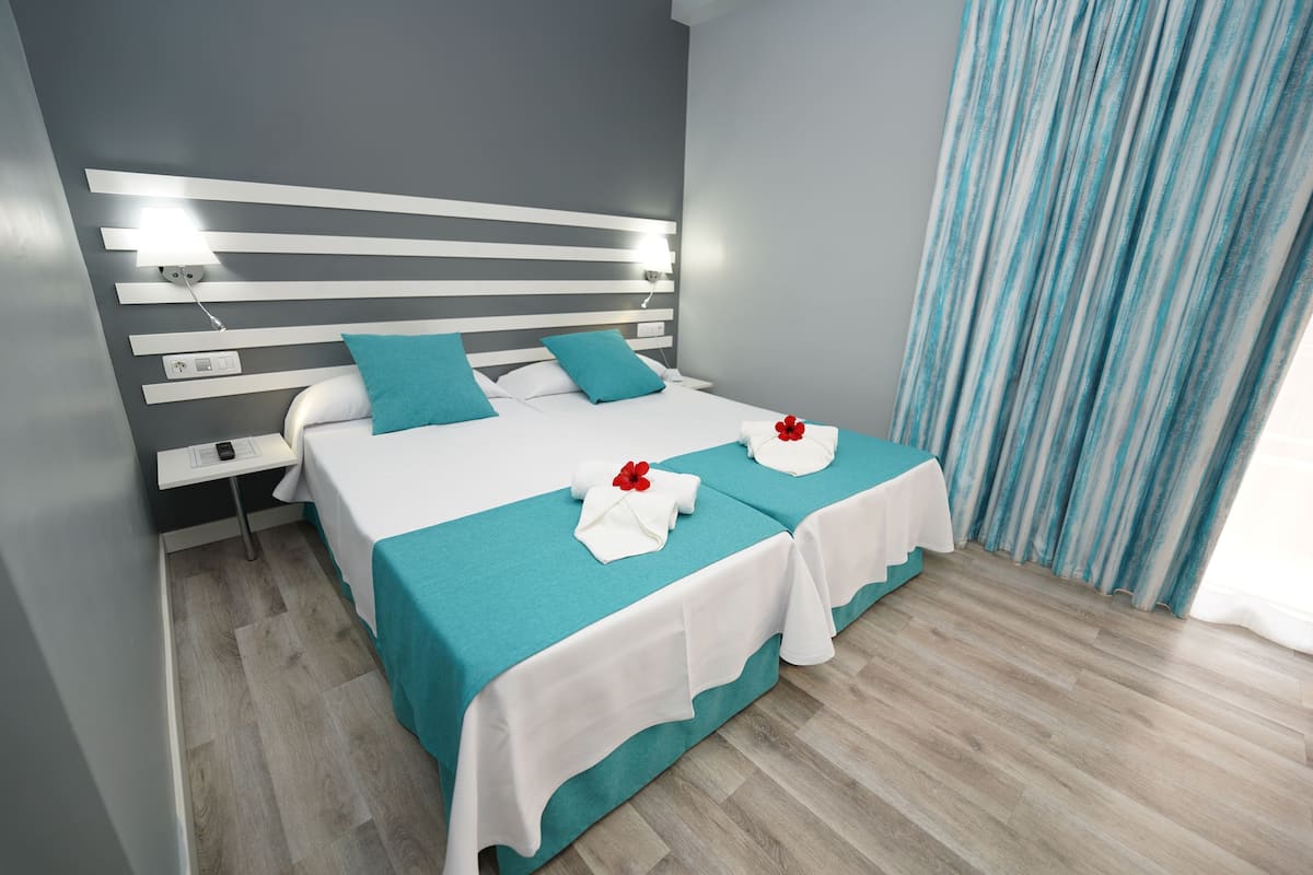 A modern hotel room with a large bed, a bedside table, and a nightstand.
