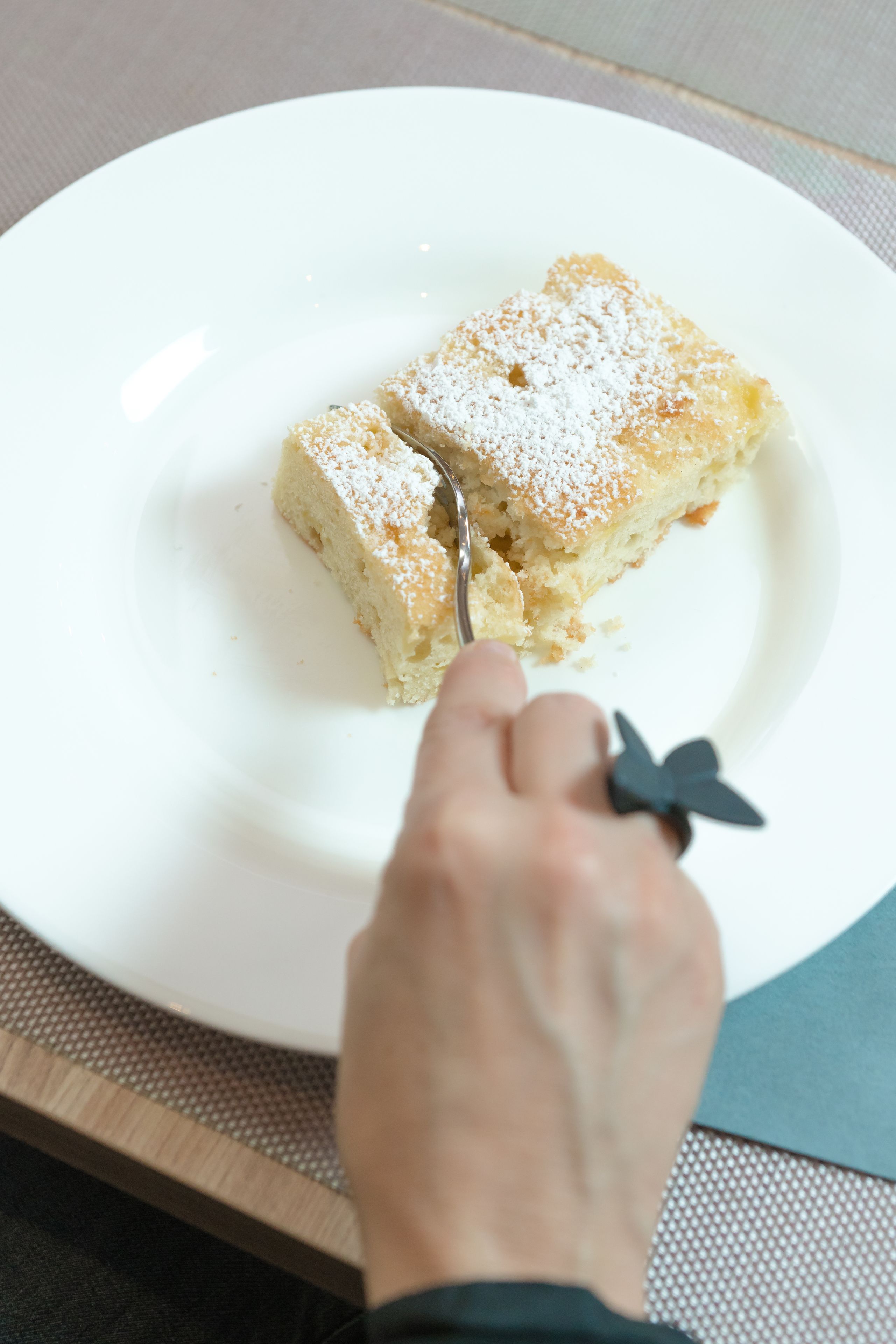 A slice of cake on a white plate with powdered sugar on top.