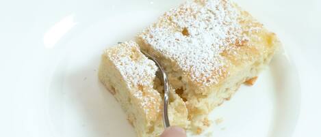 A slice of cake on a white plate with powdered sugar on top.