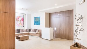 A modern hotel lobby with a reception desk, a sofa, and a coffee table. - Helios Hotel Monza (Monza)