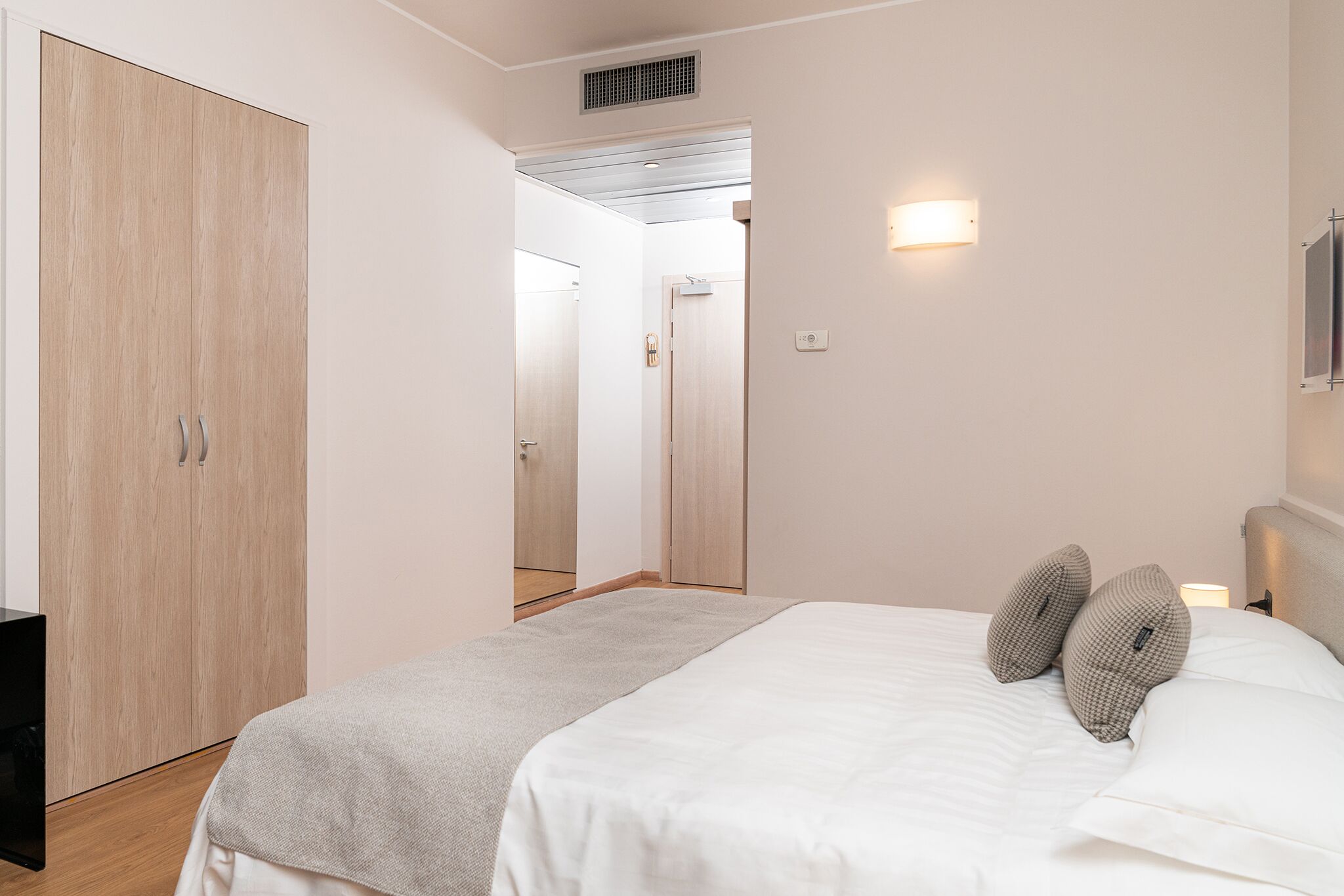 Un dormitorio con cama, armario, mesita de noche y luz empotrada.