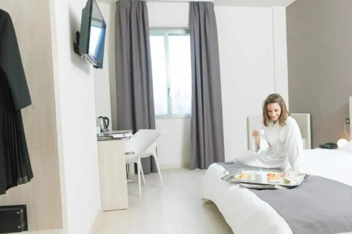 Une chambre d’hôtel moderne équipée d’un lit, d’un bureau et d’une télévision.