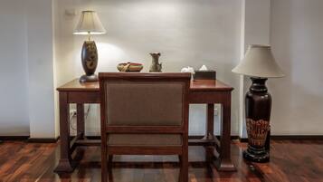 A wooden desk with a lamp, a vase, and a tissue box.