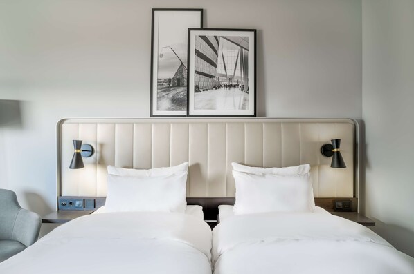 A hotel room with a large bed, two bedside tables, and two wall-mounted lamps. There are two framed pictures above the bed. - Radisson Hotel & Conference Centre Oslo Airport (Ullensaker)