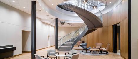 Un hall d’entrée spacieux, doté d’un escalier moderne, de coins salon confortables et d’un plafond haut orné de luminaires originaux.