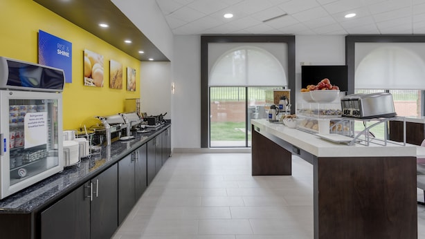 Una cocina moderna con una pared de acento amarilla, una isla grande con provisiones para el desayuno y vistas a través de la puerta de cristal.