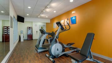Un gimnasio con cintas de correr, una bicicleta estática y un banco.