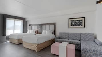 A modern hotel room with two beds, a sofa, and a framed picture on the wall.