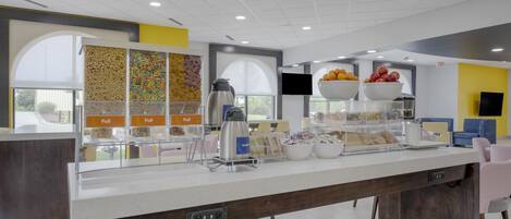 Un bar à petit-déjeuner moderne, équipé d’une machine à café, de corbeilles de fruits et d’une variété de viennoiseries.